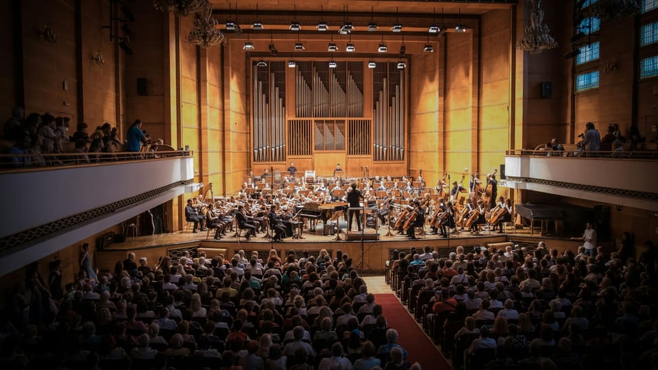 An audience watching an orchestra in a large concert hall