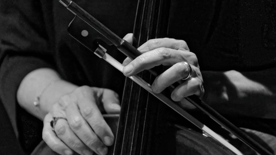 Black-and-white close-up of a cellist's hands and bow