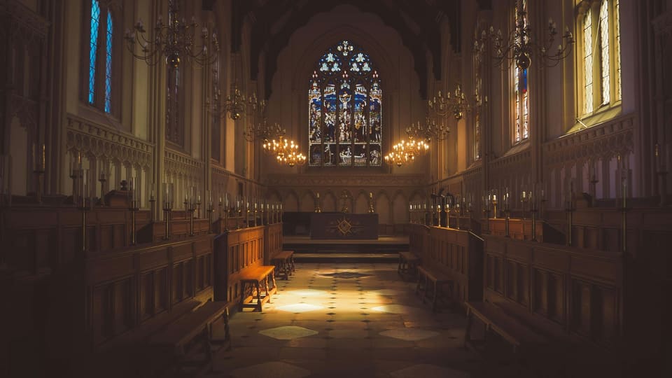 A church interior with stained-glass windows and wooden pews