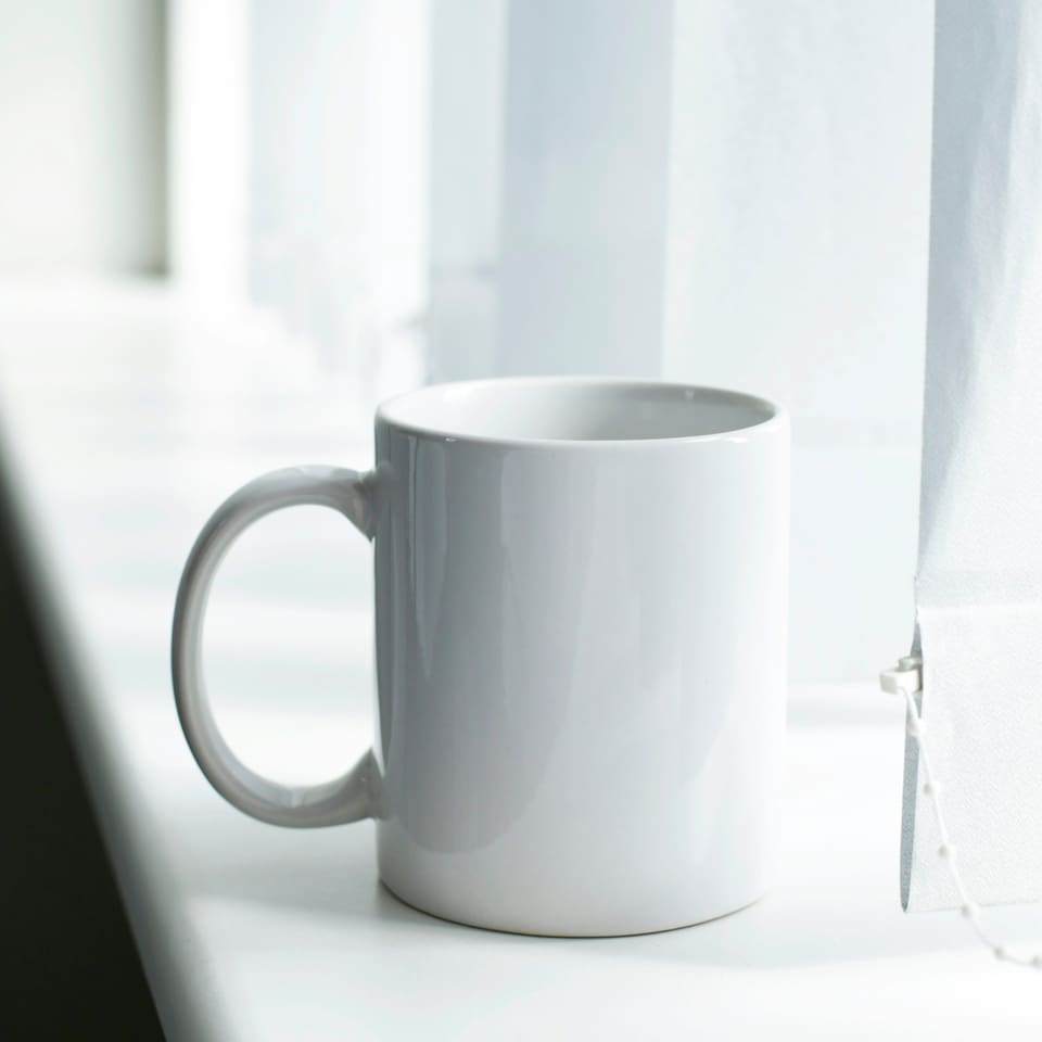 A plain white mug on a windowsill