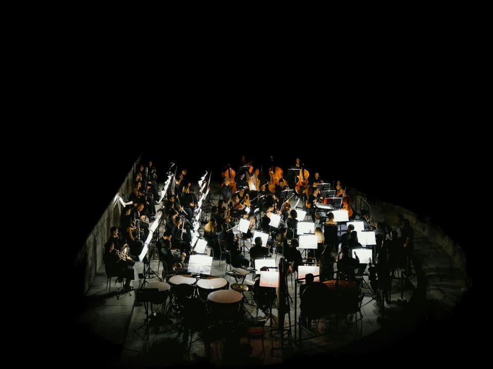 An orchestra seen from above on a dark stage