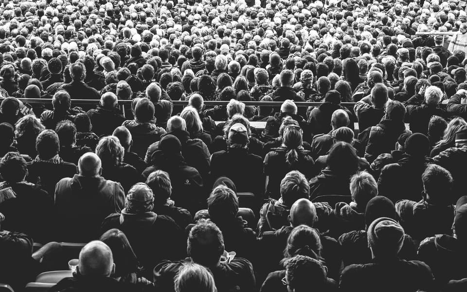 A large audience seen from behind, in black and white
